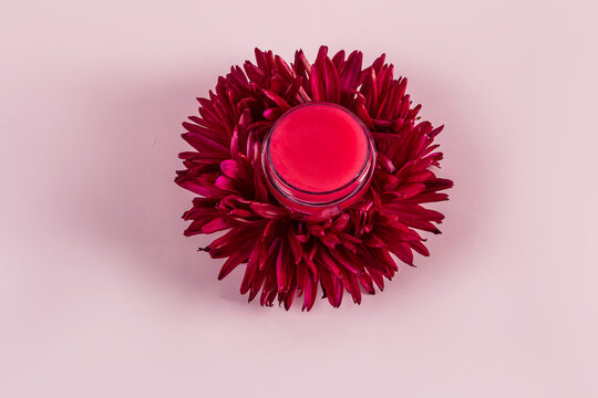 Cosmetic jar on red aster flower for skincare elegance