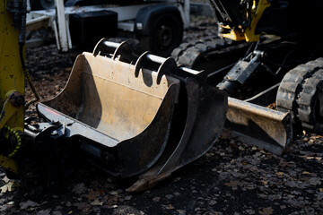 Excavator with dual digging attachments and rubber crawler tracks on outdoor construction surface showing mechanical structure, hydraulic connections, and industrial worksite setup
