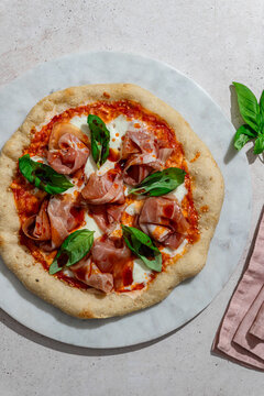 Delicious pizza with ham, basil, and fresh burrata cheese