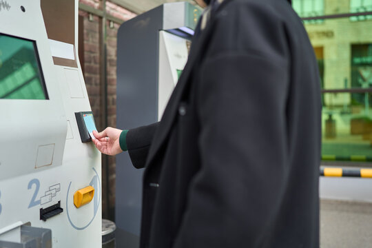 Young man paying at ticket machine in autumn city setting