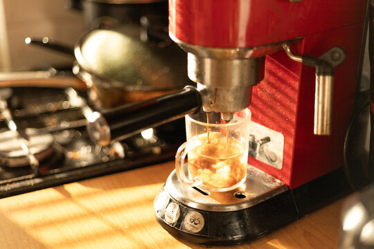 Morning coffee brewing in a red kitchen coffee machine