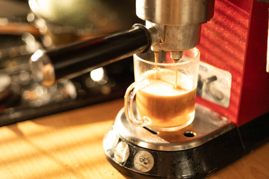 Brewing fresh coffee at home using a red espresso machine