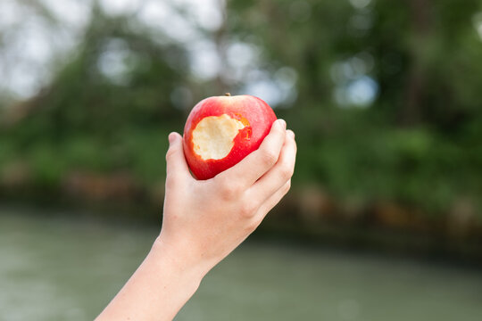 Child holding a bitten apple outdoors