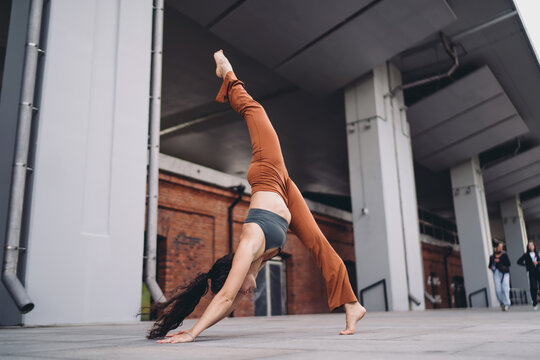 Athletic woman in yoga three-legged downward dog pose, one leg lifted upward. Conceptual wellness photo representing empowerment, flexibility, balance, mindfulness, and digital lifestyle.