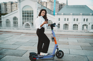 Businesswoman using smartphone while standing on electric scooter. Conceptual stock photo...