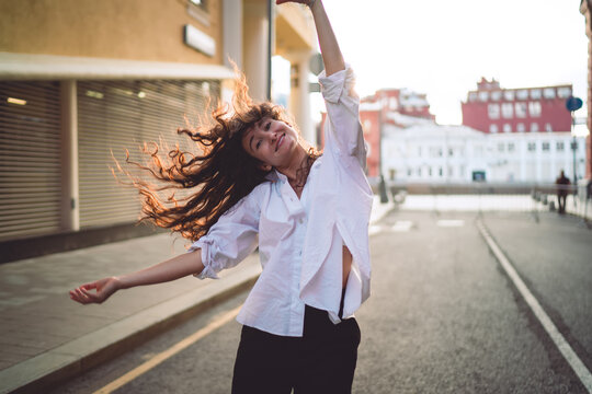 Smiling woman with flowing hair holds smartphone, moving freely outdoors. Conceptual stock photo symbolizing empowerment, individuality, digital identity, and freedom in modern lifestyle expression.