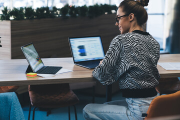 Modern businesswoman working with multiple digital devices, turning away from screen while...