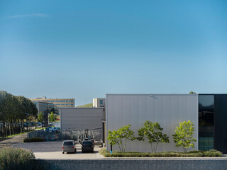 Contemporary commercial facility with metal cladding parking area and clear blue sky backdrop