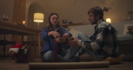 Couple enjoys wrapping gifts together in cozy living room during holiday season