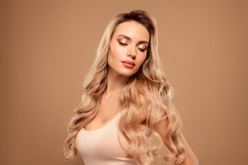 Naklejka premium Charming young woman posing with long blonde hair and glamour style on beige background