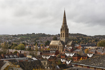 Fototapeta premium High view point of St Michael and All Angels Church, nestled among the rooftops of Exeter. It clearly shows the spire standing above the houses. There is space for text