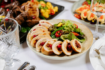 Roasted chicken rolls with cranberries and fresh salad served on festive holiday table