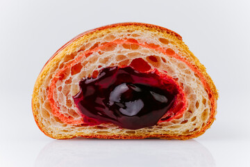 Close-up of fresh croissant with berry filling and vibrant layers on white background