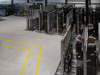 Industrial warehouse with vertical storage racks holding window frames and glass units with yellow safety markings