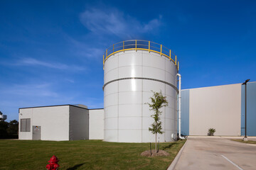  97,000 Gallon Carbon Bolted Steel water Tank, with low Profile Roof and warehouse behind it