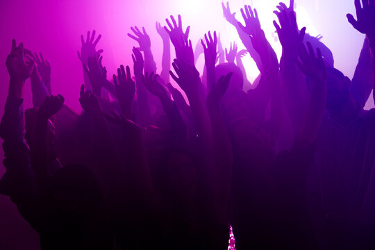 Energetic crowd dancing at a purple neon party full of music and celebration in a vibrant nightclub scene