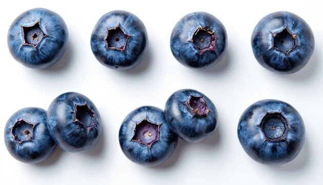 Collection of ripe blueberries arranged on a clean white surface. Each berry shows its natural bloom and star shaped blossom end detail. These fresh fruits are perfect for healthy eating visuals.