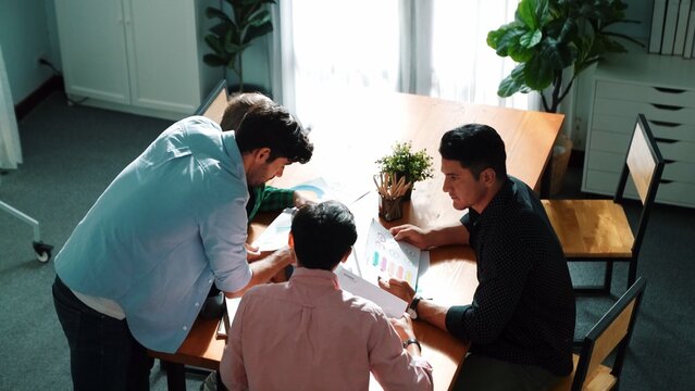 Top view of diverse group brainstorming marketing idea while looking at financial graph or stock market statistic chart report. Skilled business team share plan about start up project. Convocation. - Powered by Adobe