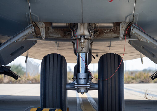 Front landing gear viewed from below the fuselage showing open gear bay doors and connected hydraulic lines
