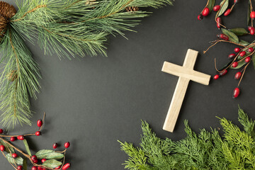 Cross with evergreen and berry frame on a black background © Kara