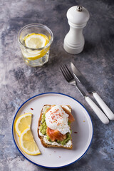Healthy breakfast with poached egg on toast, avocado and salmon.