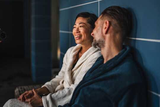 Diverse couple relaxing at spa wearing bathrobes feeling happy - Powered by Adobe