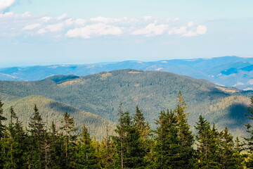 Fototapeta premium Lush green mountains stretch under a clear blue sky in a tranquil landscape view
