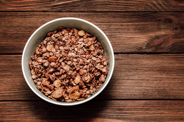 Bowl of chocolate granola on wooden table ready for breakfast or snack