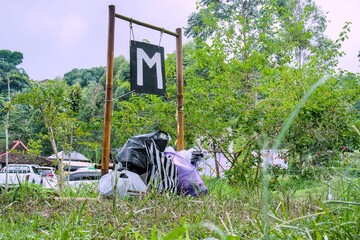 A sign with the letter m in the middle of a lush green garden