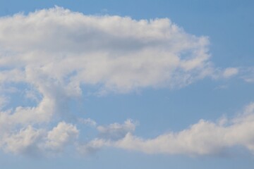 Bright blue sky with soft white clouds on a sunny day. Clean and natural background ideal for design and creative use.
