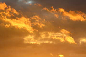 Bright orange and golden clouds glow in the evening sky after a passing rain, symbolizing calm and renewal.
