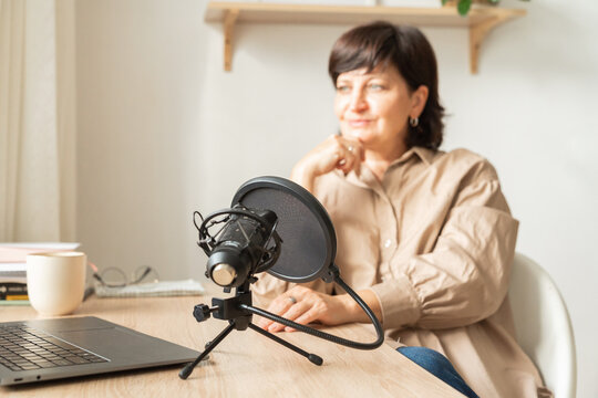 Woman podcasting at home office, recording audio content