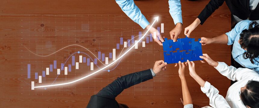 A group of diverse professionals collaborates at a desk, arranging puzzle pieces amidst a rising graph, symbolizing teamwork and business growth in a modern workplace. Axiom