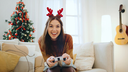 Happy woman enjoys a festive atmosphere playing video games together while surrounded by Christmas...