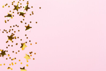 Golden star shape confetti on color background, top view