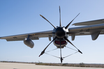 Ground maintenance operation showing propeller blade secured by tie down straps on military transport aircraft parked on apron