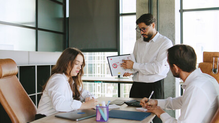 Three professionals in a contemporary office collaborate on project updates, brainstorming solutions, and taking notes during an important meeting.