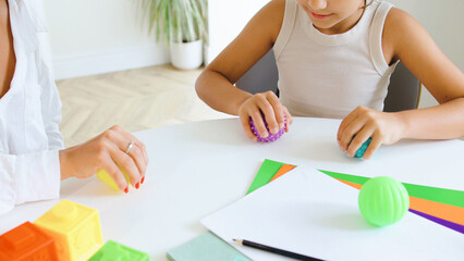 Children's therapy session focusing on speech improvement using hands-on activities and sensory toys in a bright, modern setting