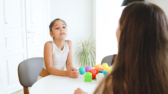 Session between speech therapist and child focused on letter recognition with alphabet and communication skills in a bright, modern therapy room with educational toys