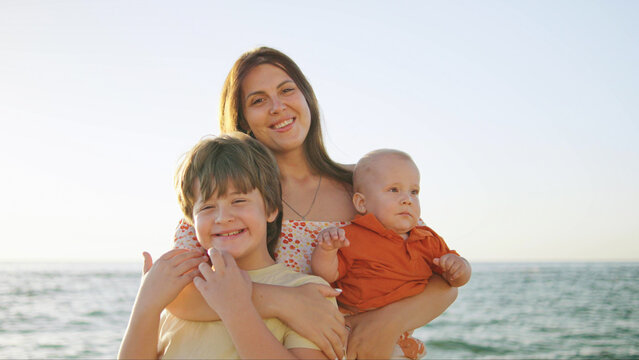 Joyful mother with two children enjoying a sunny day at the beach during late afternoon - Powered by Adobe