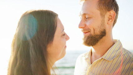 Fototapeta premium Couple enjoying a sunny day at the beach, sharing smiles and love while the ocean waves roll in, capturing a moment of joy in the warm light of the afternoon