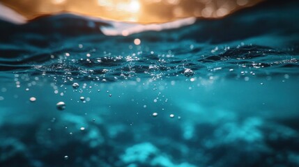 Close-up underwater view of bubble droplets rising toward the water surface with warm sunlight shining from above during a calm ocean moment