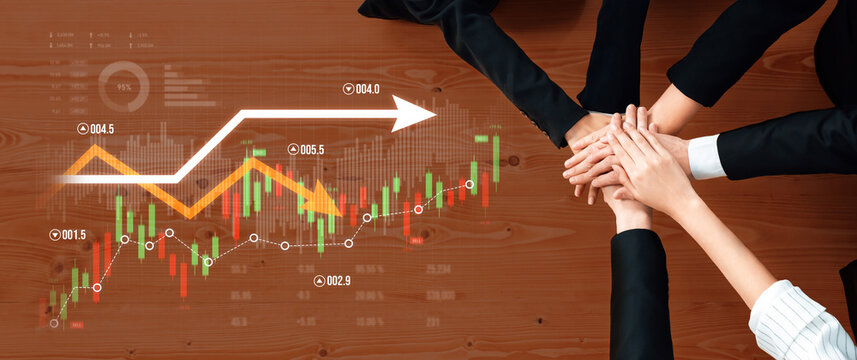A dynamic business scene capturing teamwork with hands stacked on a wooden table, showcasing financial growth through charts and graphs in the background. Scalp