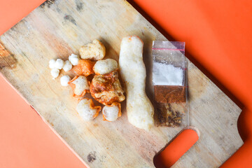 Crackers, cuanki, noodles, and complete dry seblak seasoning on a wooden tray