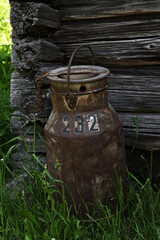 an old rusty milk can with the number 232 painted on it