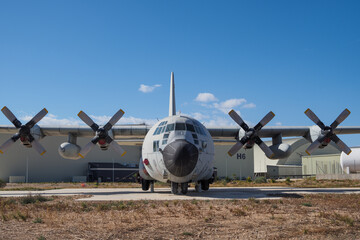 Frontal perspective of an old transport aircraft with four propellers preserved as a monument on open airfield