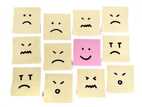 Hand drawn sad faces emoji on sticky notes with on that stands out in a smile emoji, positive way concept	
