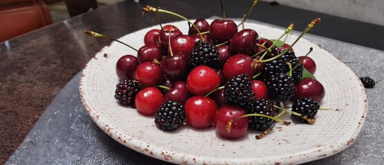 A vibrant plate of red cherries and blackberries arranged artfully.