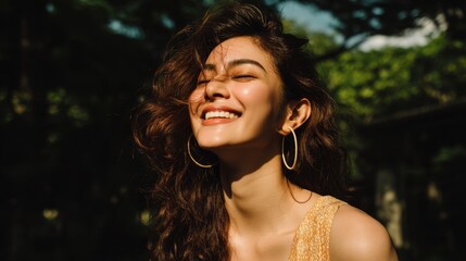 Cheerful young woman with curly hair enjoying sunlight in a natural outdoor setting, wearing a yellow outfit and large earrings, exuding joy and happiness