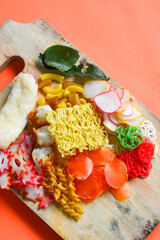Crackers, cuanki, noodles, and complete dry seblak seasoning on a wooden tray